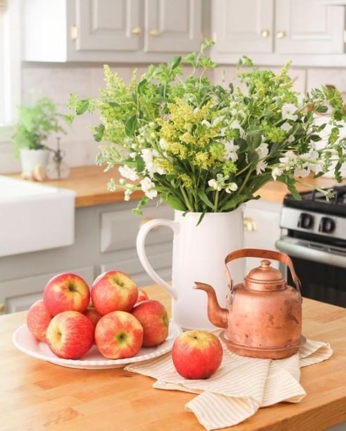 Herbstdeko keittiössä kypsiä omenoita valkoinen posliini ruukku syksyn kukkia